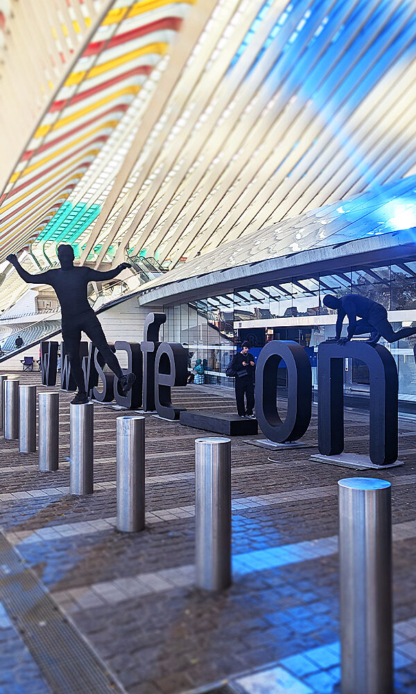 Urban installation with black silhouettes interacting with giant letters spelling “safe/on”.
