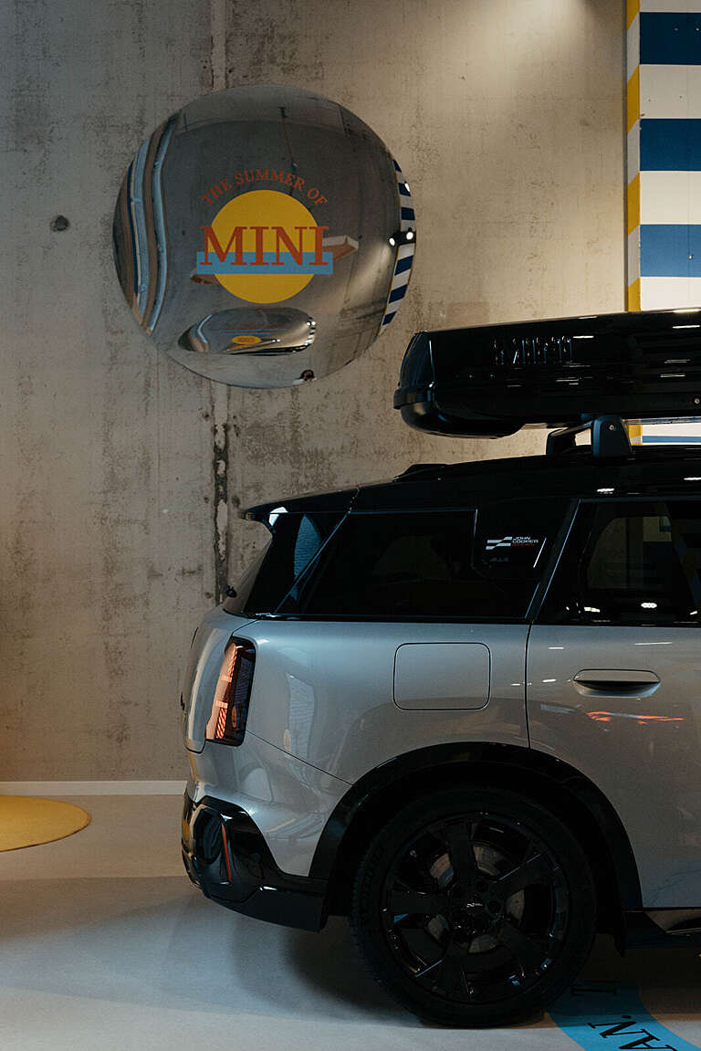 Une MINI argentée exposée sous une sphère réfléchissante arborant le logo MINI.