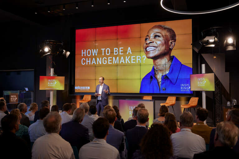 Portrait d'une femme souriante sur fond dégradé rouge et jaune avec le texte "The Buzz #2 Changemakers Everywhere.
