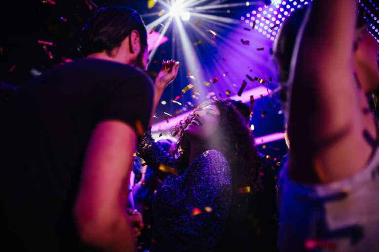 Femme dansant sous une pluie de confettis dans une ambiance festive et lumineuse, symbole de joie et de célébration partagée