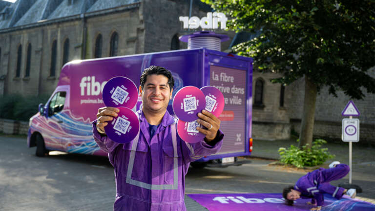 Activation terrain Proximus avec un animateur distribuant des supports de communication devant un van personnalisé