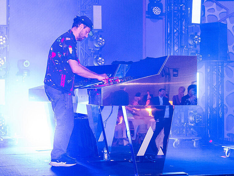A musician plays on a futuristic, light-reflecting piano during an immersive artistic session.